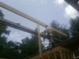 Carpenter setting a ridge beam over a new addition frame — Ice Dam Removal by Roofing Brothers in Caddo Mills