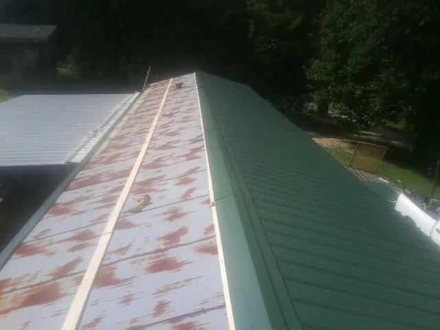 Old rusted panels beside newly installed green metal roofing — Wind Damage Roof Repair by Roofing Brothers in Caddo Mills
