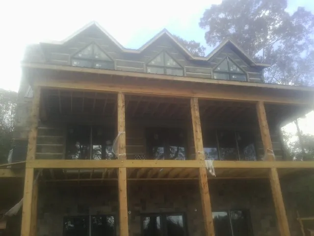 Dormers and porch framing on a large log home under construction — Roof Coating work by our crew in Caddo Mills