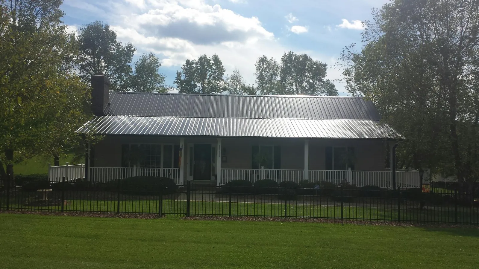 Gray metal roof on a brick ranch with a full width front porch — Gutter Guard Installation work by our crew in Caddo Mills