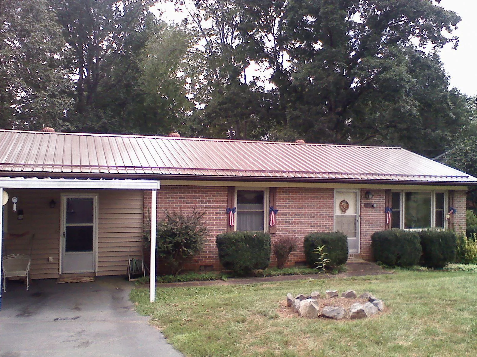Bronze metal roof and carport on a brick ranch home — Roof Repair work by our crew in Caddo Mills