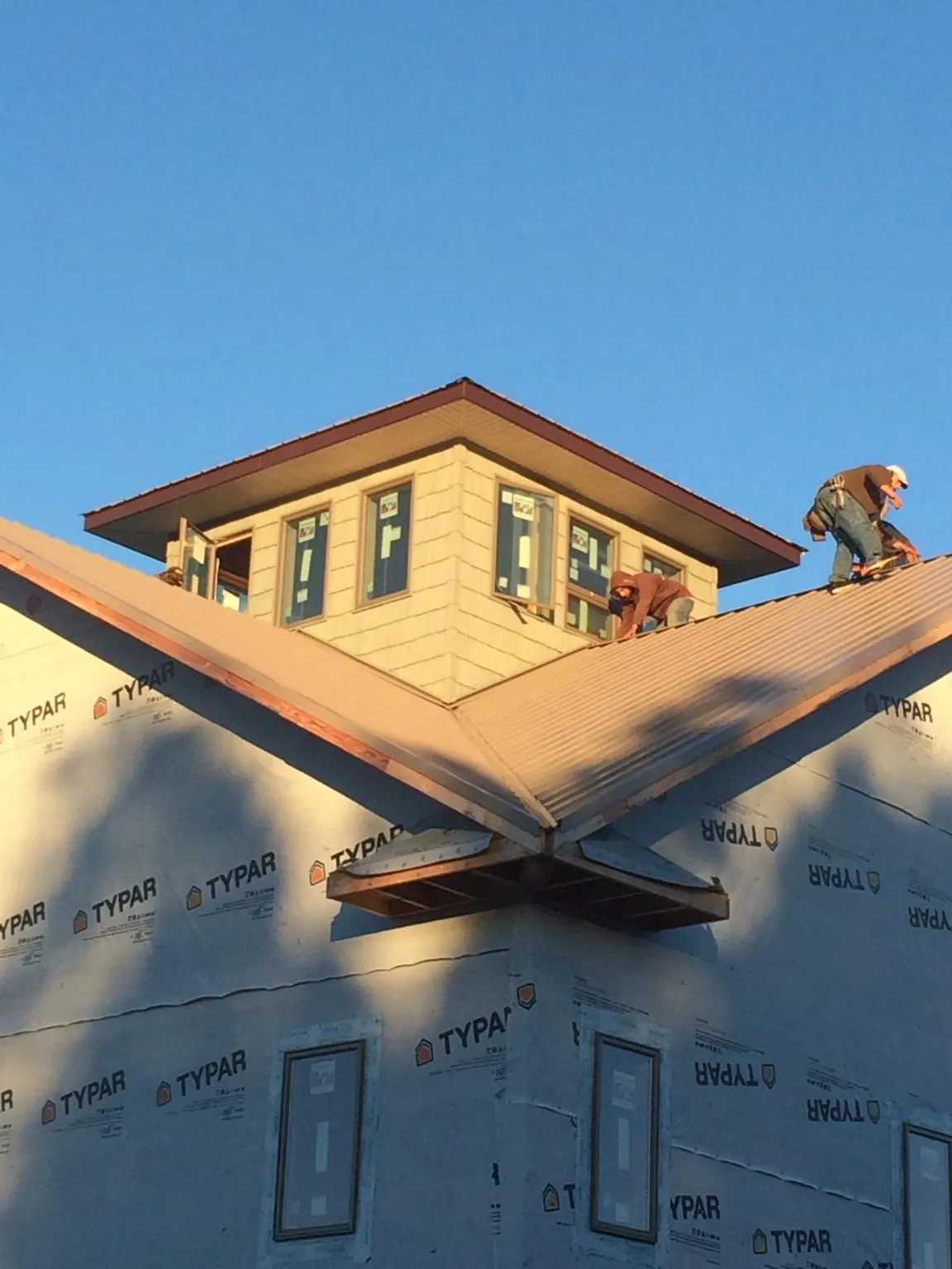 Roofers working around a rooftop cupola on a new metal roof at sunset — Roof Waterproofing in Caddo Mills by Roofing Brothers